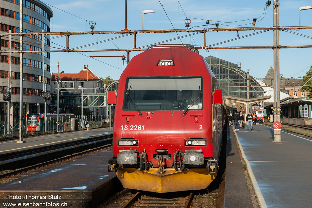 El 18 mit Zug nach Oslo
Während die El 18 an einem sonnigen Tag in Bergen auf die Abfahrt ihres Zuges nach Oslo wartet, fährt links eine Stadtbahn vorbei.
