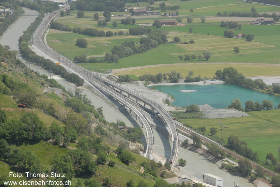Südportal Lötschberg-Basistunnel
Blick vom Wanderweg entlang der Südrampe auf das Südportal des Lötschberg-Basistunnels. Während sich ein EW4-Pendel auf Testfahrt kurz vor dem Portal befindet, näher sich im Hintergrund vom Bahnhof Visp her ein zweiter Zug, der anschliessend über das andere Gleis in den Tunnel fährt.
