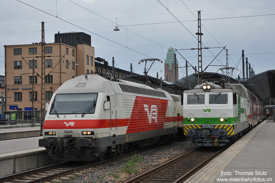 Sr2 + Sr1 in Helsinki
In Finnland ist die Typenvielfalt bei den elektrischen Streckenloks übersichtlich. Es sind nur 2 vorhanden, die passen bestens auf ein Foto.
Links die neuere Sr2, die Breitspur-Version (1524mm) der Re460, es sind 46 Loks in Betrieb (Ablieferung 1996 - 2003), vorwiegend vor Reisezügen.
Rechts die ältere Sr1 aus sowjetischer Produktion (abgeliefert 1973 - 1984), davon sind noch 110 Loks in Betrieb.
