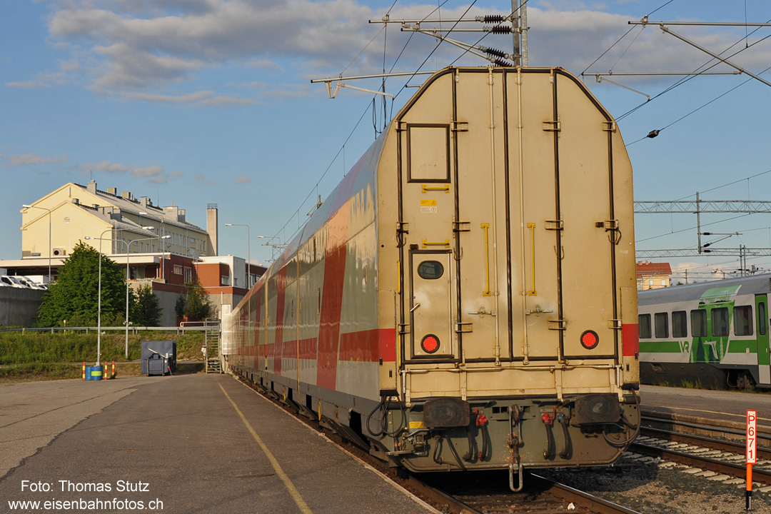 Doppelstock-Autotransportwagen
Im Bahnhof Rovaniemi hat der Nachtzug aus Kemijärvi einen längeren Aufenthalt. Nebst Lokwechsel (und Wegstellen des Aggregatwagens) werden
zusätzliche Schlafwagen sowie die Autotransportwagen beigestellt. Diese stehen hier noch an der im Hintergrund sichtbaren Verladeanlage (mit 2 Rampen).

