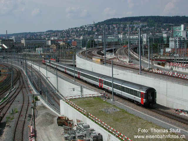 Ausbauten Zürich HB (2)
Immer noch auf dem Dach des Unterwerks, jetzt mit Blick Richtung Vorbahnhof. Ganz links 2 Gleise vom Vorbahnhof nach Wiedikon (Gleise mit altem, dunklem Schotter). Rechts daneben die Doppelspur "Altstetten Süd" vom Vorbahnhof, die im Tunnel verschwindet, um die Wipkinger S-Bahn-Gleise zu unterqueren. Auf dem Gleis 591 wird ein IC mit Lok rückwärts in den HB eingeschoben. Über dieses Gleis kann ab Vorbahnhof mittels einer Brücke (ohne den Zugsverkehr zu stören) auch die Abstellanlage Herdern erreicht werden.
