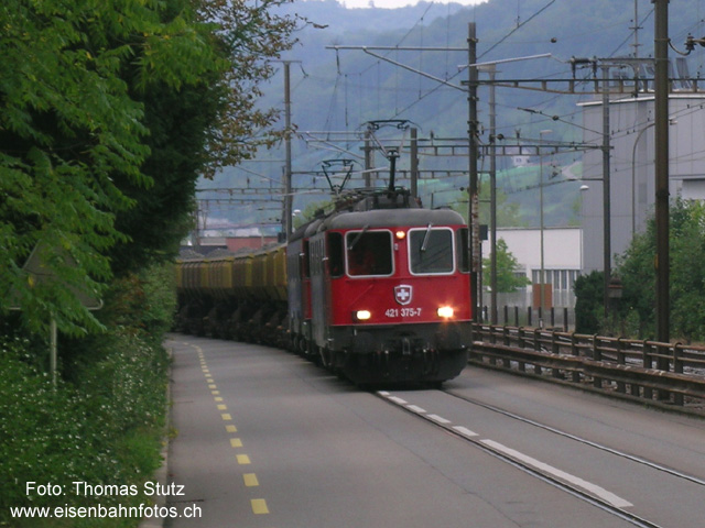 SBB Cargo auf der Strasse
SBB Cargo geht auf die Strasse! Um in Sissach vom Anschlussgleis, wo das Ausbruchmaterial der Umfahrung Sissach verladen wird, in den Bahnhof Sissach zu gelangen, wurde in der Strasse nach Itingen ein Gleis verlegt, das auch mit Fahrleitung ausgerüstet ist. Die ganze Anlage ist mit einer Barriere gesichert. Mit mehreren Hundert Metern ist es wohl einer der längsten Bahnübergänge!
