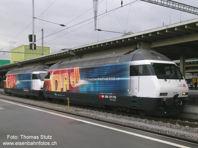 2 x Radio DRS
Nach der DRS1-Lok, die schon einige Wochen unterwegs ist, gibt es jetzt auch eine passende DRS3-Lok. Die Loks wurden auf die Namen "DRS 1" (460 073-0) und "Uf u dervo" (460 015-1) getauft. Hier warten die Loks vor der Taufe auf die Einfahrt in die Halle.
